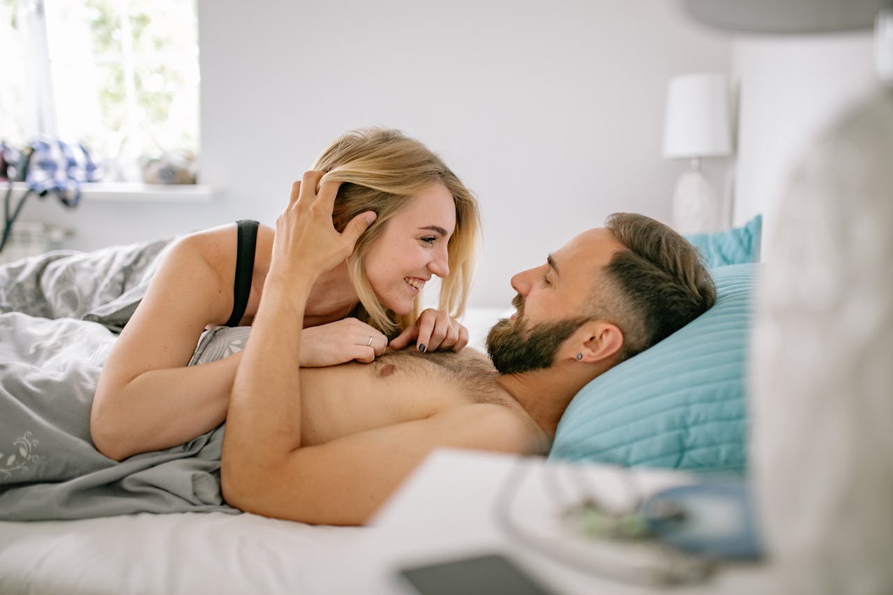 A cheerful couple enjoying a tender moment in a cozy bedroom setting.