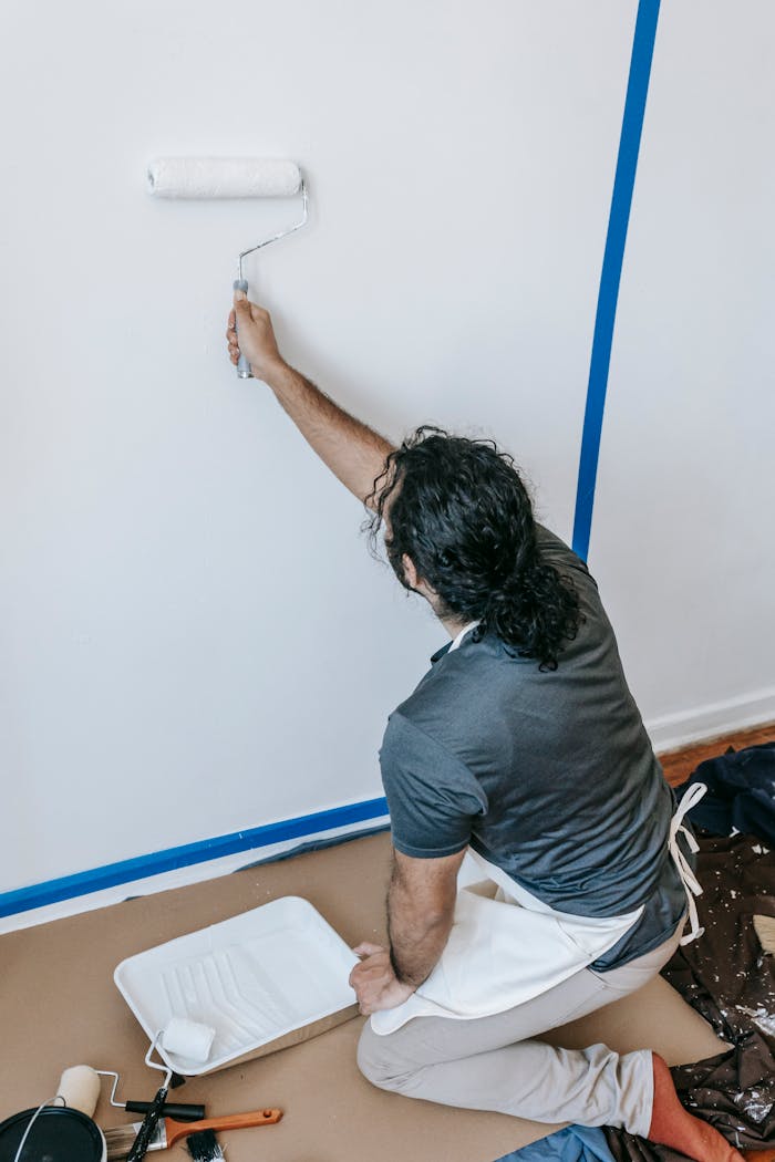 Adult man painting a wall with a roller during a home renovation project indoors.